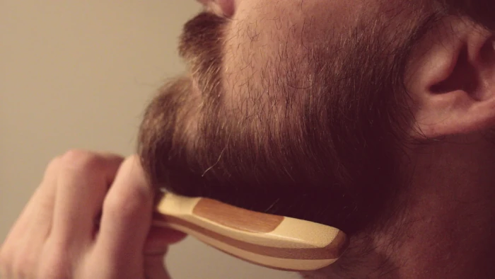 cómo suavizar la barba, persona cepillándose.